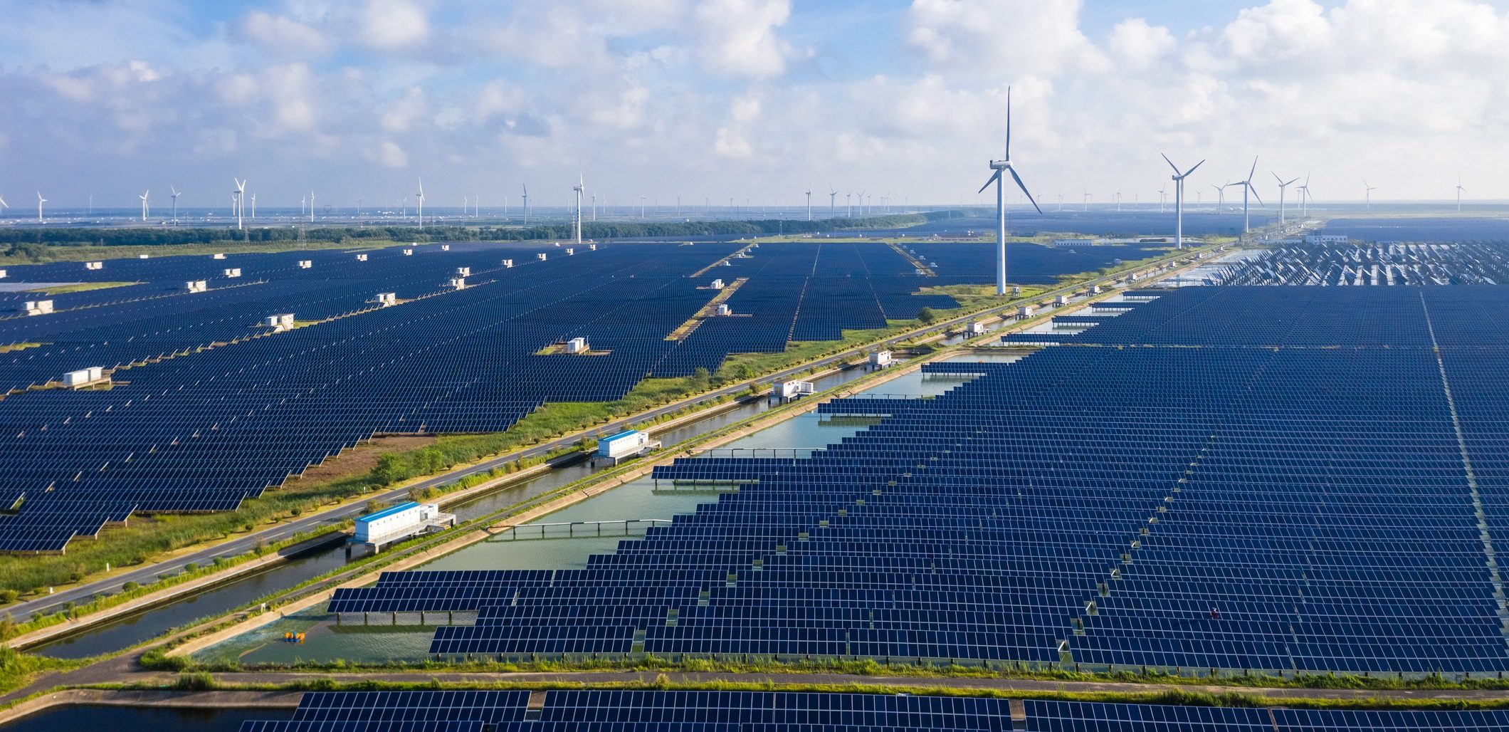 Solar power stations in plain areas, wind turbines in the distance. Yancheng City, Jiangsu Province, China.